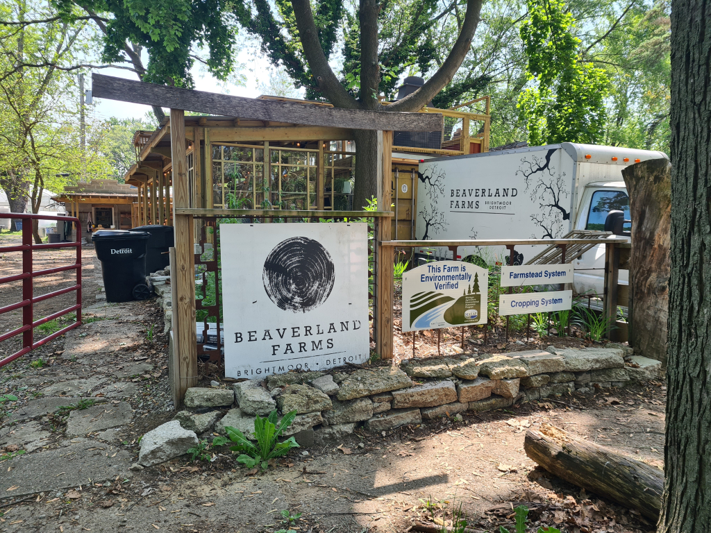 a sign reading Beaverland Farms set in front of a rustic but beautiful entrance to an urban farm